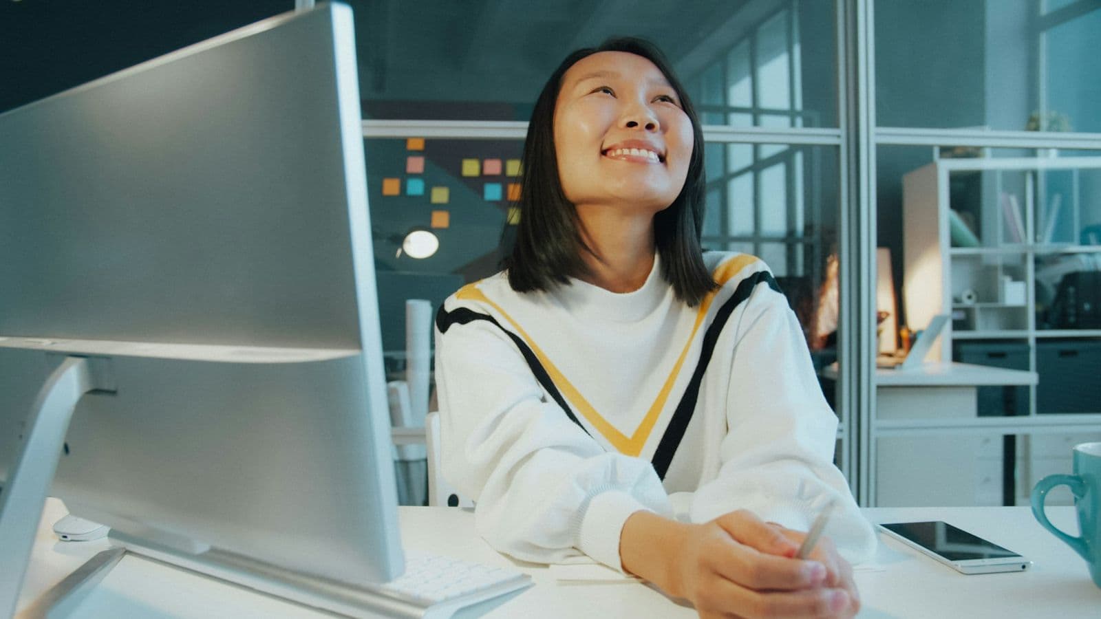 A woman smiling at her computer in a bright office