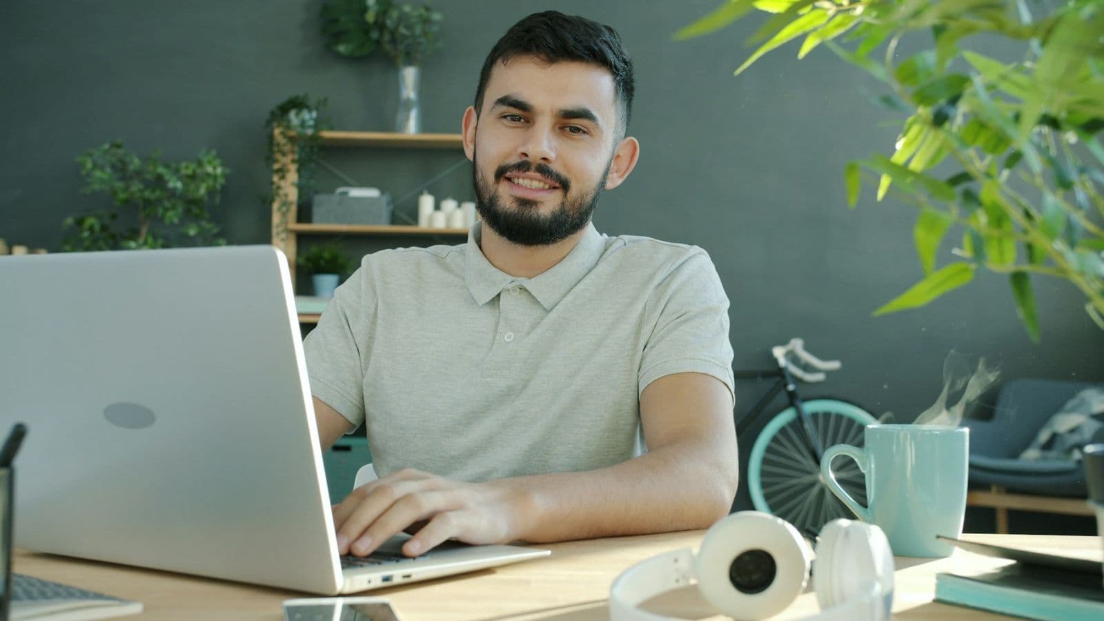 A man smiling while reading feedback on his laptop